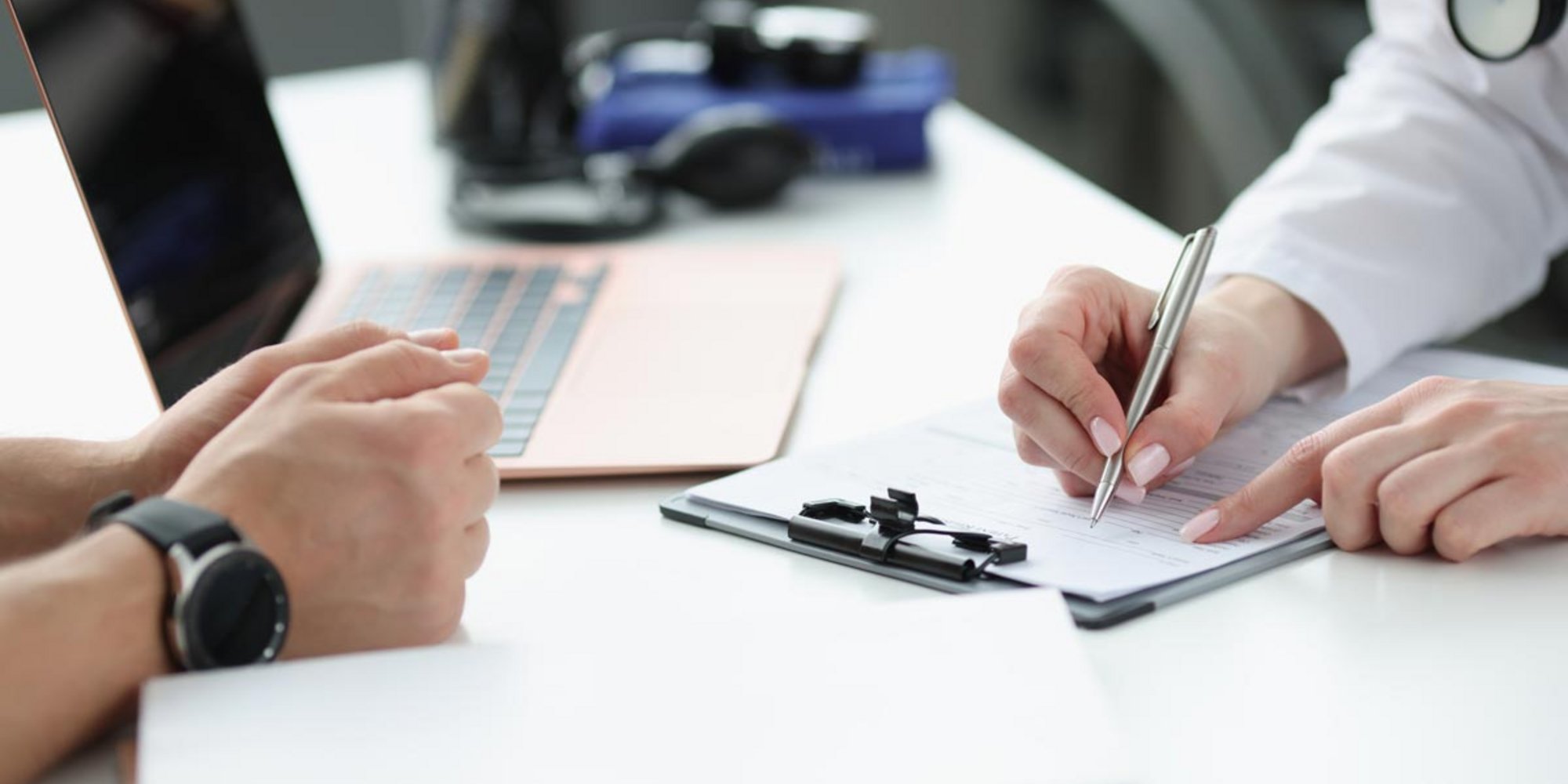Versicherungsgespräch: Formular wird gemeinsam am Schreibtisch ausgefüllt.